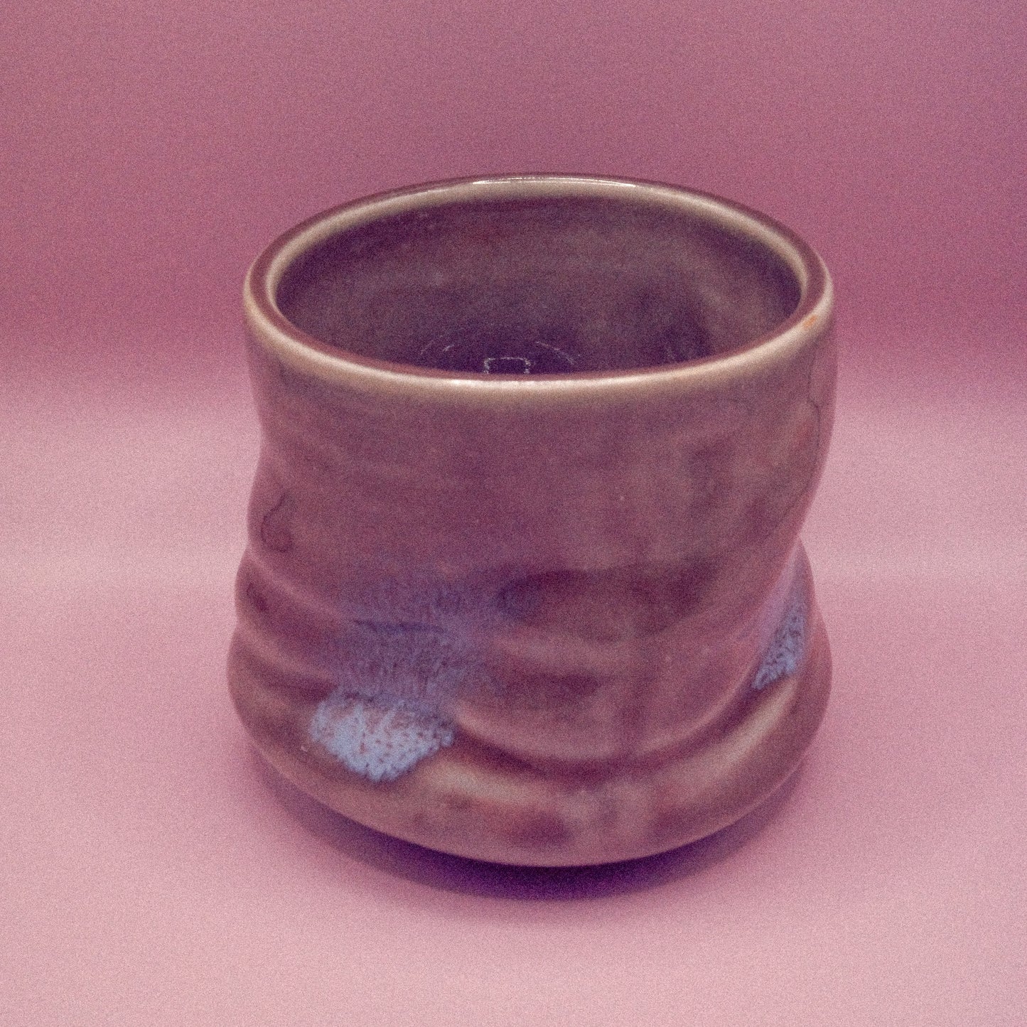 Ceramic cup with ribbed texture on a pink background