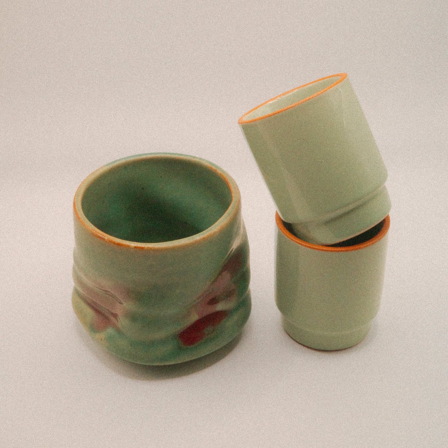Two green ceramic cups stacked on a white background