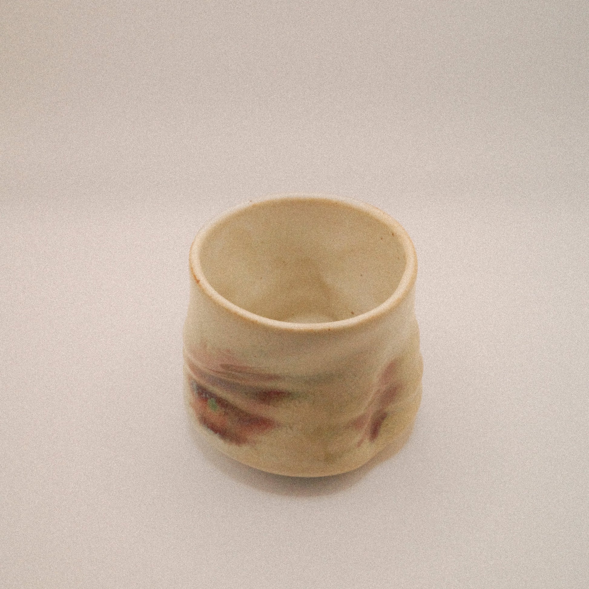 Small ceramic cup with marbled design on a plain background